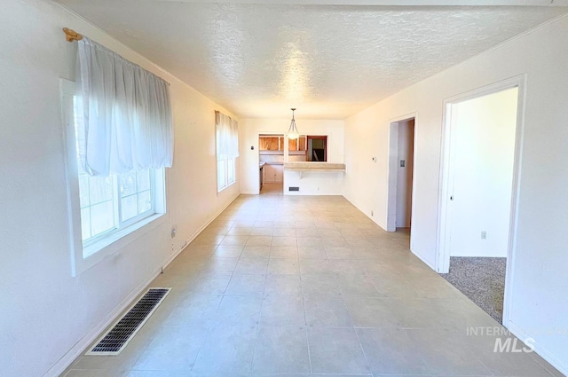 interior space featuring visible vents, a textured ceiling, and baseboards