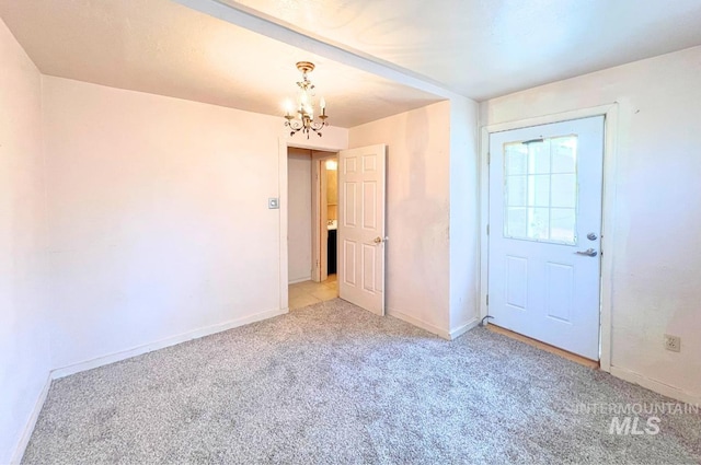 unfurnished room with an inviting chandelier, baseboards, and light colored carpet