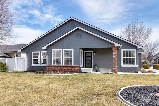 view of front of home with a front yard, a gate, brick siding, and fence