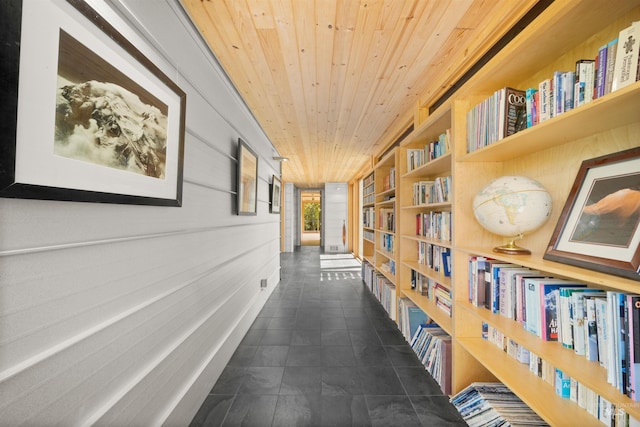 hall featuring wooden ceiling, wood walls, built in shelves, and tile patterned flooring