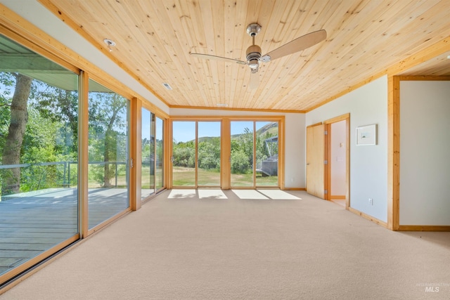 unfurnished sunroom with wood ceiling, carpet flooring, a mountain view, and baseboards