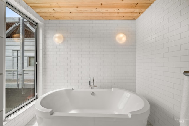 full bath with tile walls, wood ceiling, and a freestanding tub