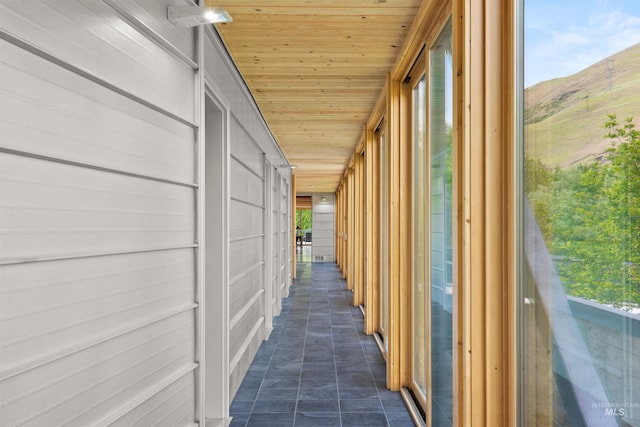 hall with wood ceiling, a mountain view, and healthy amount of natural light