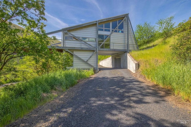 view of side of home featuring asphalt driveway and a carport