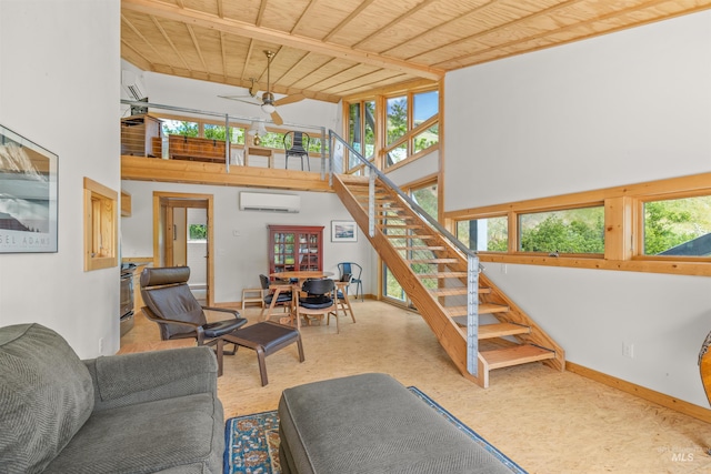 living area with a wall unit AC, stairs, a towering ceiling, a ceiling fan, and baseboards