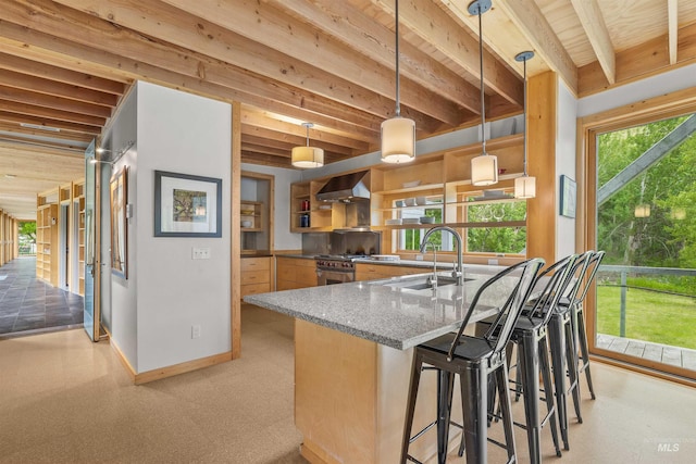 kitchen with a sink, wall chimney range hood, stone countertops, baseboards, and a breakfast bar
