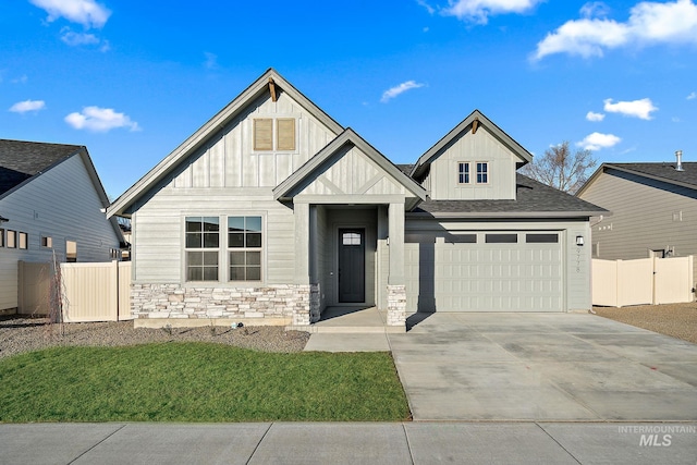 view of front of property with a garage, fence, concrete driveway, stone siding, and board and batten siding