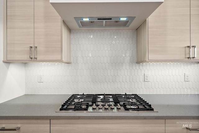 kitchen featuring light brown cabinetry, decorative backsplash, and stainless steel gas stovetop