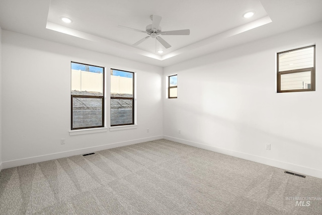 unfurnished room featuring baseboards, visible vents, a raised ceiling, carpet floors, and recessed lighting