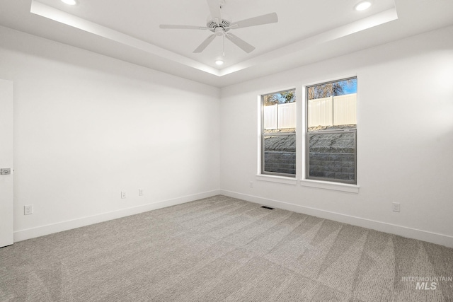 carpeted spare room featuring a raised ceiling and recessed lighting