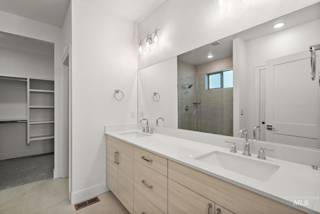 bathroom featuring a stall shower, tile patterned flooring, a sink, and visible vents