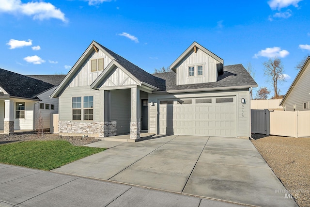 view of front of house featuring board and batten siding, a gate, fence, stone siding, and driveway