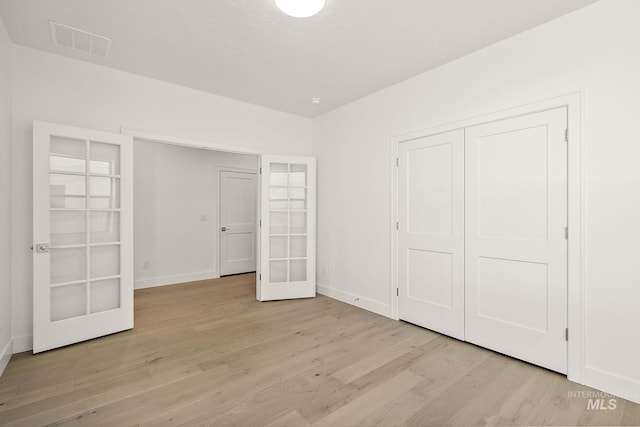 unfurnished bedroom with light wood-style flooring, a closet, visible vents, and baseboards