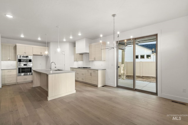 kitchen with stainless steel appliances, a sink, light wood-style floors, light countertops, and decorative backsplash