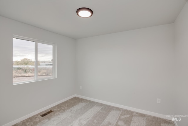 spare room with baseboards, visible vents, and light colored carpet