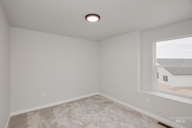 carpeted spare room with visible vents and baseboards