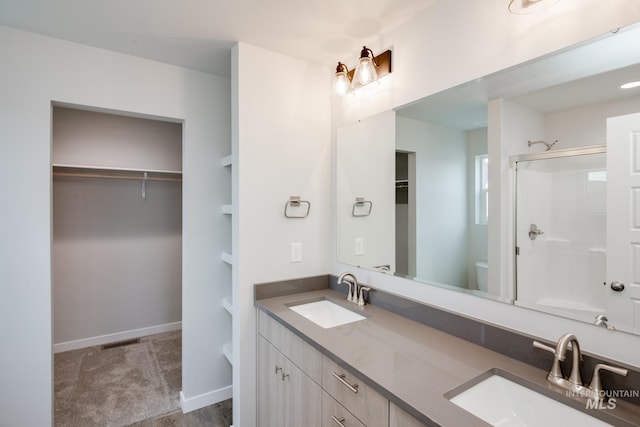 bathroom with a spacious closet, an enclosed shower, a sink, and toilet