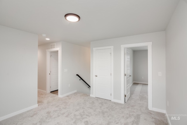 empty room featuring visible vents, baseboards, and light colored carpet