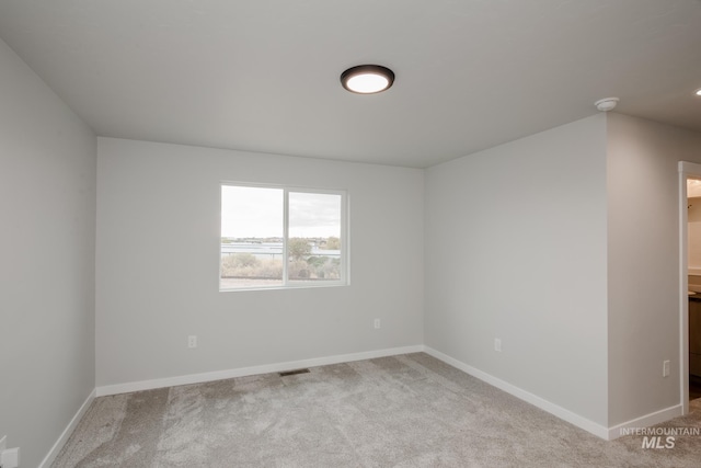 spare room featuring carpet floors, visible vents, and baseboards