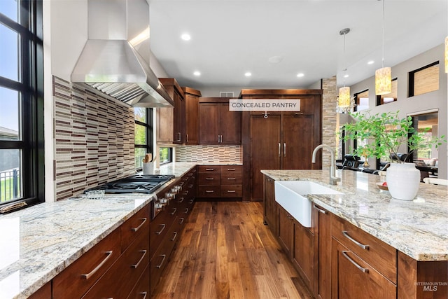 kitchen featuring exhaust hood, backsplash, dark wood-style flooring, a sink, and stainless steel gas stovetop