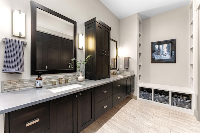 bathroom with a sink, built in features, backsplash, and double vanity