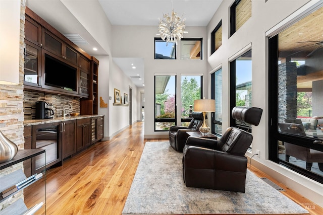 living room with a towering ceiling, baseboards, light wood-type flooring, and a notable chandelier