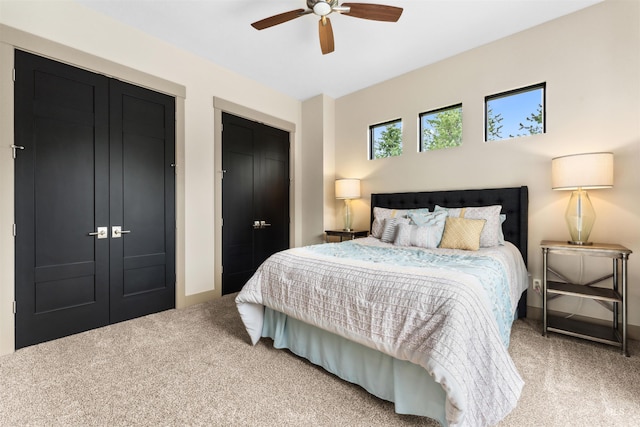 bedroom featuring carpet floors, ceiling fan, and two closets