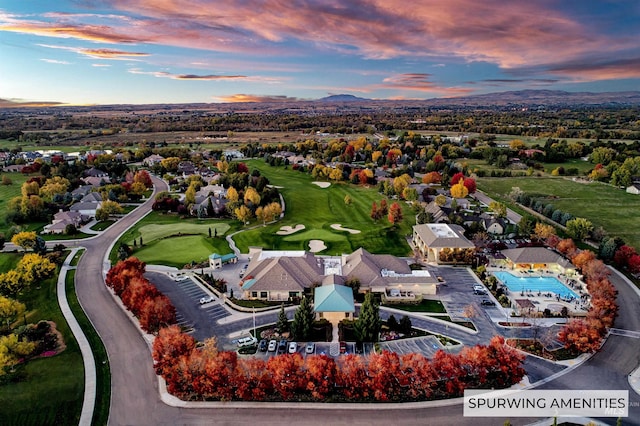aerial view at dusk featuring a mountain view and golf course view