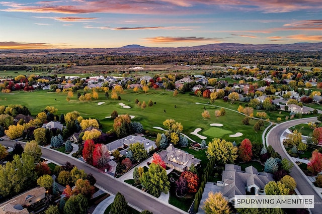 aerial view at dusk featuring a residential view, a mountain view, and golf course view