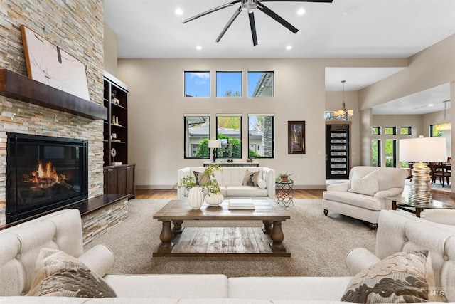 living room with a ceiling fan, a fireplace, wood finished floors, baseboards, and recessed lighting