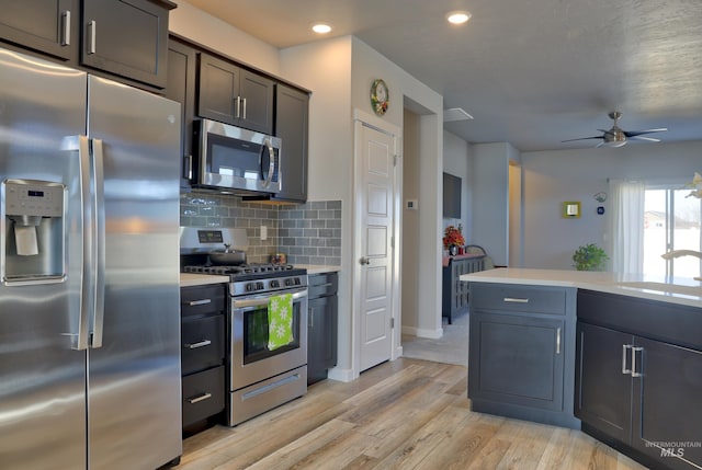 6240 W Black Butte St, Meridian, ID 83646 - kitchen with light countertops, light wood-style flooring, decorative backsplash, a ceiling fan, and appliances with stainless steel finishes