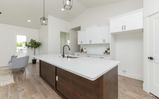 2117 Oxon St, Caldwell, ID 83605 - kitchen featuring white cabinetry, light countertops, light wood-style floors, a kitchen island with sink, and decorative backsplash