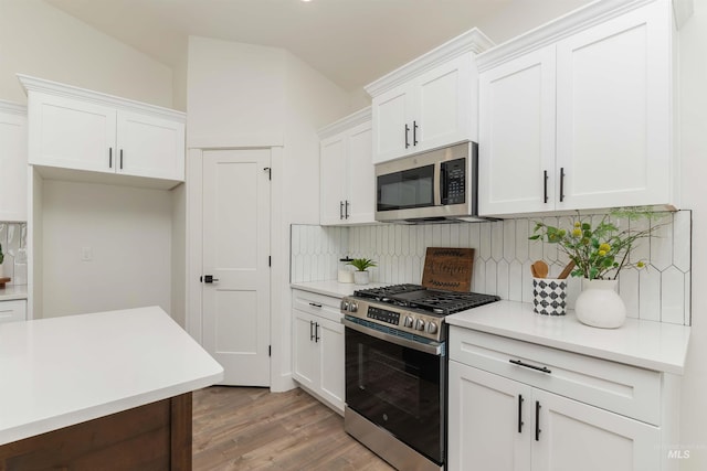 2117 Oxon St, Caldwell, ID 83605 - kitchen with stainless steel appliances, backsplash, light wood-type flooring, white cabinets, and vaulted ceiling