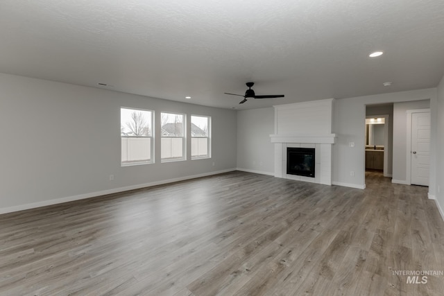 14761 N Ninja Way, Nampa, ID 83651 - unfurnished living room with light wood-style flooring, a tile fireplace, baseboards, and a ceiling fan