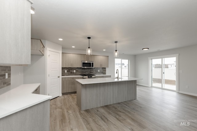 14761 N Ninja Way, Nampa, ID 83651 - kitchen with an island with sink, a sink, light countertops, light wood-style floors, and stainless steel microwave