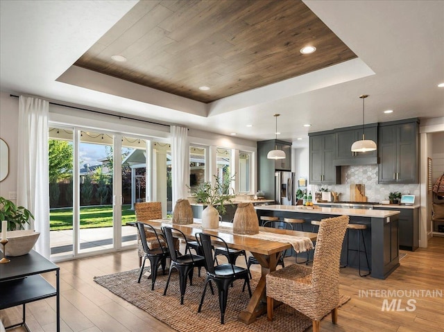 dining space with wooden ceiling, recessed lighting, a tray ceiling, and light wood-type flooring