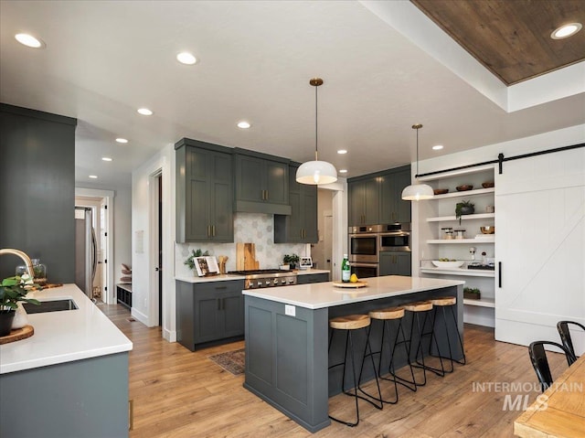 kitchen with a sink, recessed lighting, light wood-style floors, a kitchen bar, and open shelves