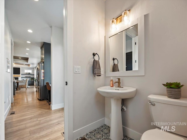 half bathroom with toilet, baseboards, visible vents, recessed lighting, and wood finished floors