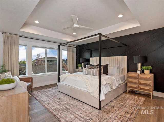 bedroom featuring wood finished floors, a tray ceiling, and recessed lighting