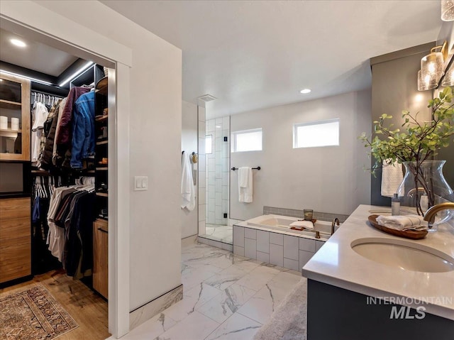 full bath with recessed lighting, a spacious closet, vanity, a bath, and a stall shower