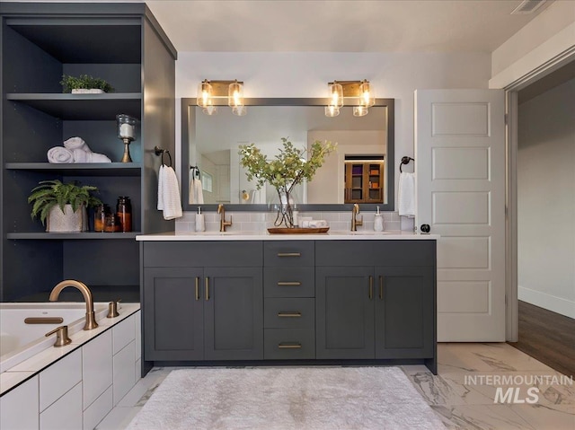 full bathroom with double vanity, a garden tub, marble finish floor, and a sink