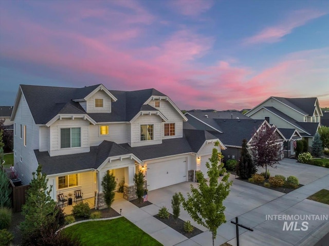 view of front of house featuring an attached garage, driveway, stone siding, and a porch