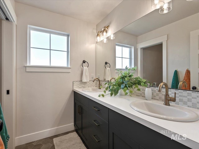 full bath with baseboards, a sink, double vanity, and tasteful backsplash