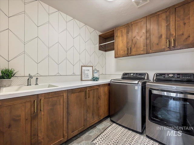 laundry room with cabinet space, visible vents, a sink, and separate washer and dryer