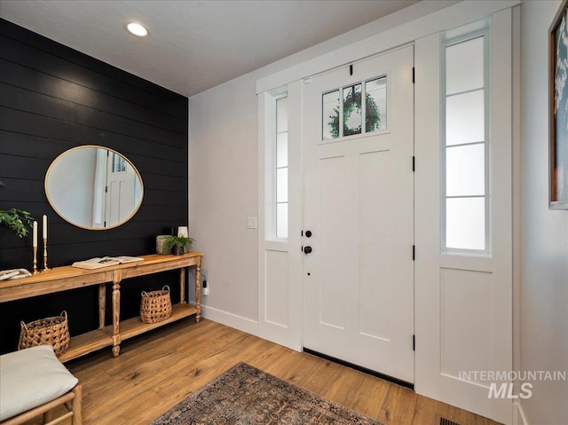 foyer entrance featuring recessed lighting, baseboards, wood walls, and light wood-type flooring