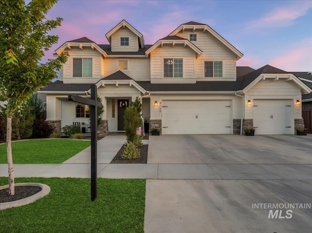craftsman-style house with stone siding, an attached garage, a front yard, and concrete driveway