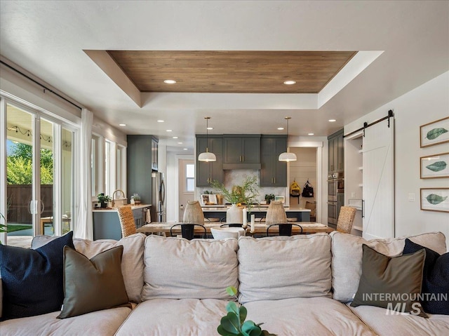 living room featuring recessed lighting, a raised ceiling, and a barn door