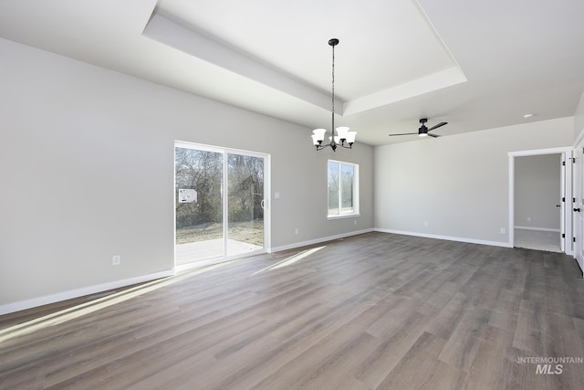 interior space featuring hardwood / wood-style flooring, a raised ceiling, and ceiling fan with notable chandelier