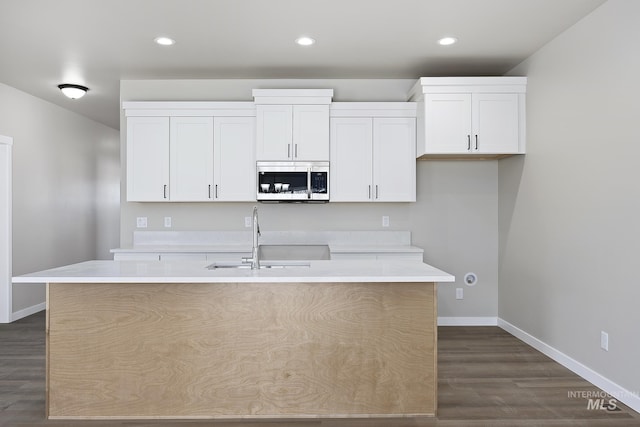 kitchen with sink, an island with sink, white cabinetry, and dark hardwood / wood-style floors