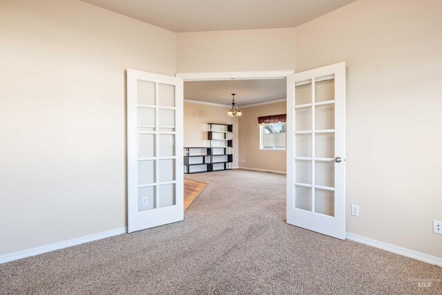 carpeted spare room with french doors and a chandelier